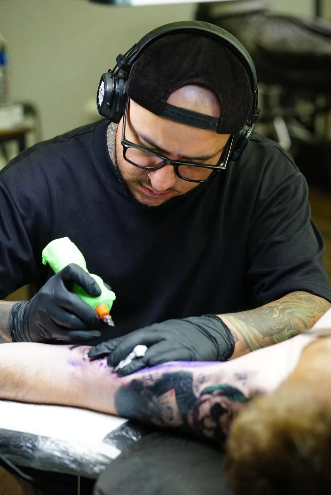 Cbastian arbetar koncentrerat på en tatuering