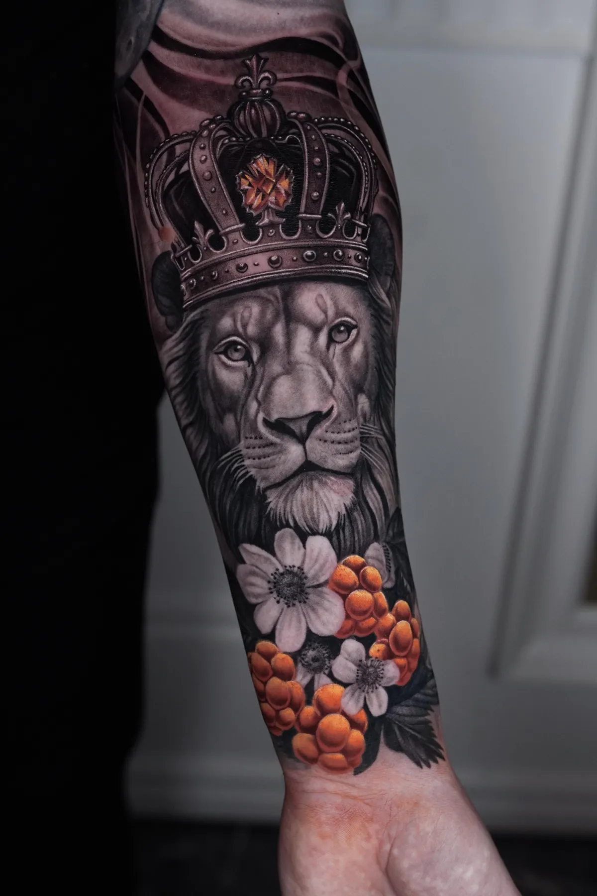 Lejon med krona och orange bär tatuerat på underarmen