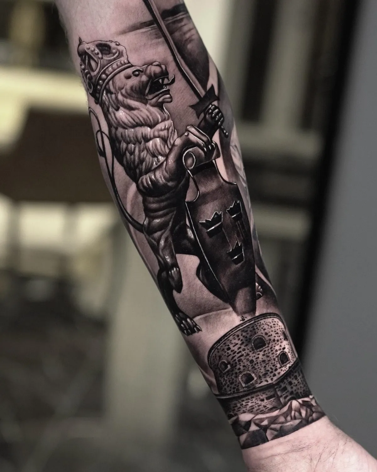 Heraldiskt lejon med svenska tre kronor tatuerat på underarmen