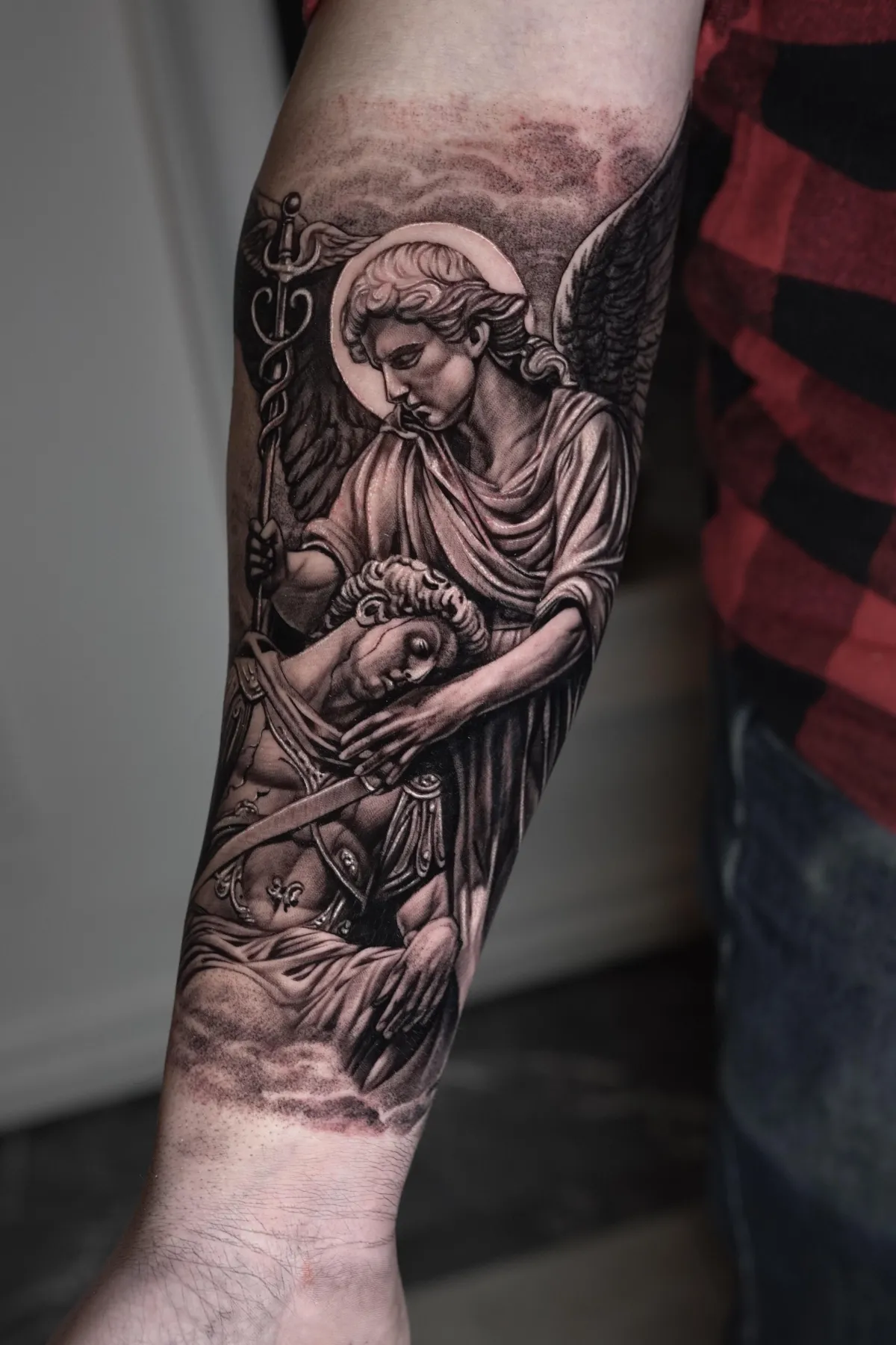 Ärkeängel med svärd tatuerad i black and grey på underarmen